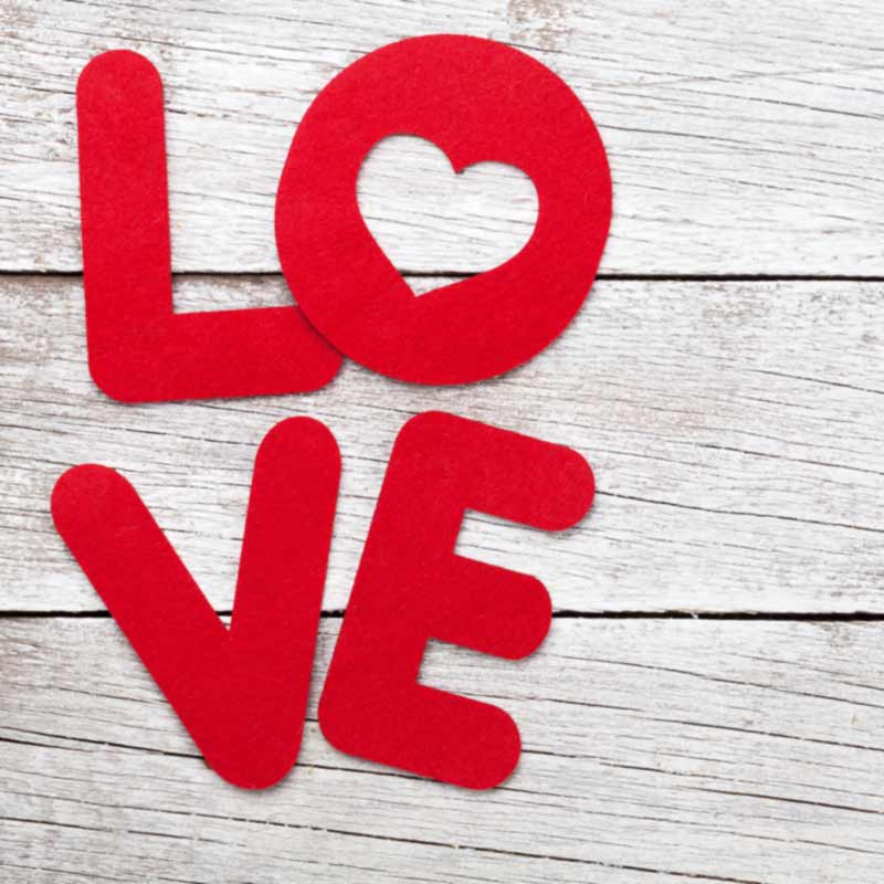 'Love' in fuzzy felt letters on a white wooden background